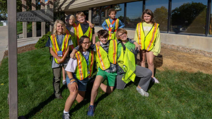 Eight students in bright yellow safety vests pose